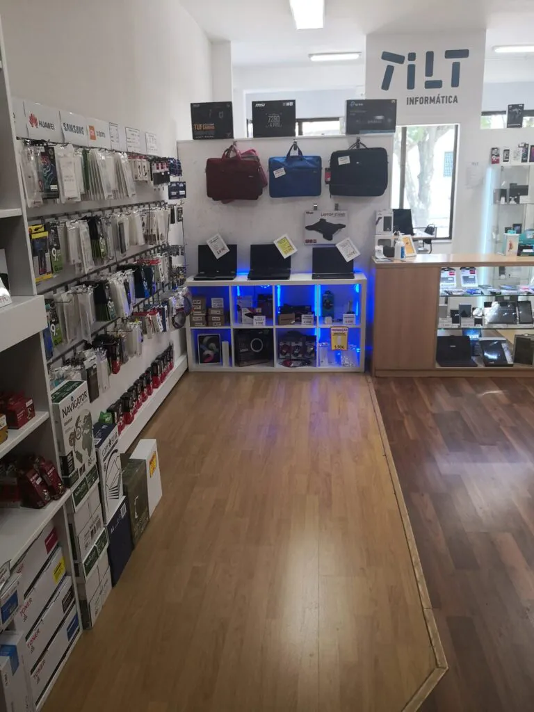 Interior da loja de informática em Rio Tinto com diversos produtos expostos, computadores, telemóveis, portáteis, capas, mochilas, etc